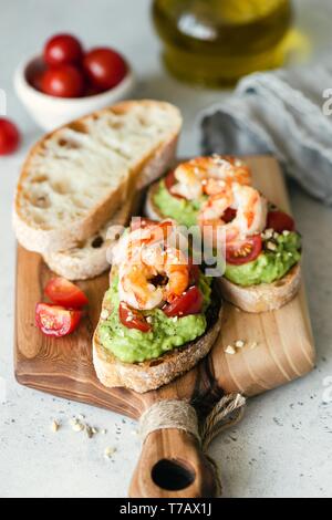 Toast mit Avocado und Garnelen auf Holz serviert. Gesundes Frühstück, Aperitif Stockfoto