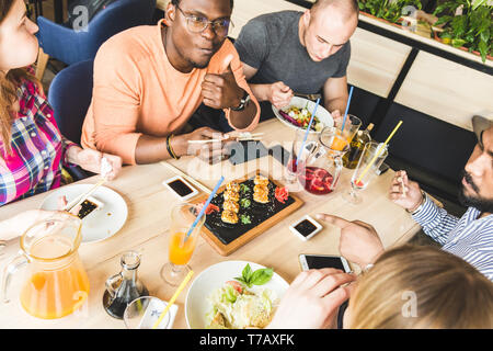 Ansicht von oben. Ein Unternehmen der multikulturellen Gesellschaft junge Menschen in einem Cafe essen Sushi rollen, trinken Getränke Spaß haben. Stockfoto