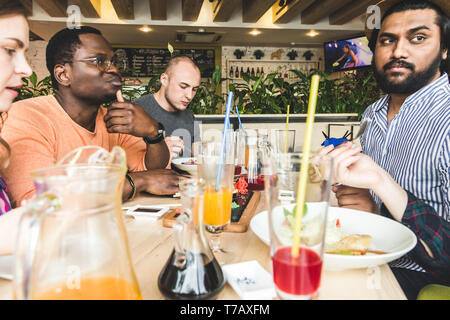 Ansicht von oben. Ein Unternehmen der multikulturellen Gesellschaft junge Menschen in einem Cafe essen Sushi rollen, trinken Getränke Spaß haben. Stockfoto