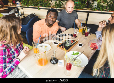 Ansicht von oben. Ein Unternehmen der multikulturellen Gesellschaft junge Menschen in einem Cafe essen Sushi rollen, trinken Getränke Spaß haben. Stockfoto