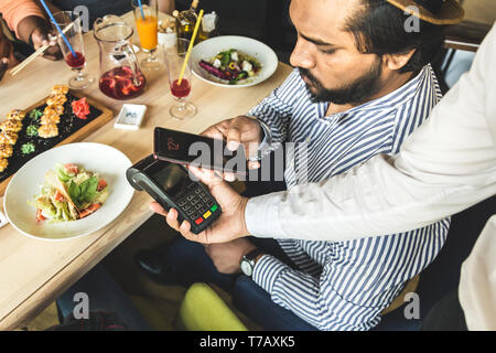 Junge attraktive hinduistischen Mann eine kontaktlose smartphone Zahlung. Stockfoto