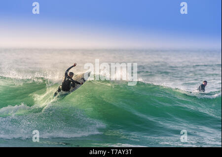 Ein surfer Carving eine Welle an den populären Surfen hotspot Fistral Beach in Newquay in Cornwall. Stockfoto