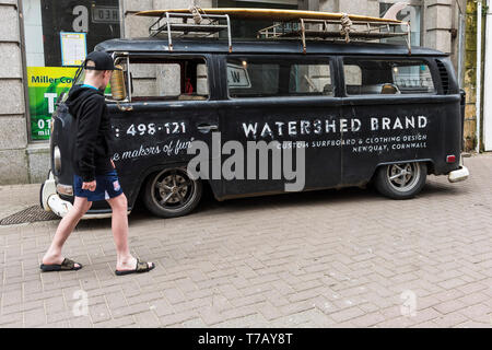 Eine junge Urlauber bewundert einen Vintage Ratte suchen Volkswagen Wohnmobil Werbung Wasserscheide Marke im Stadtzentrum von Newquay in Cornwall geparkt. Stockfoto