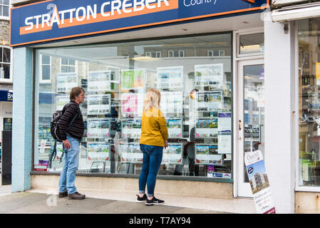 Die Leute, die auf der Suche nach Eigentum Informationen in einem Stratton Creber Immobilienmakler Fenster im Stadtzentrum von Newquay in Cornwall. Stockfoto