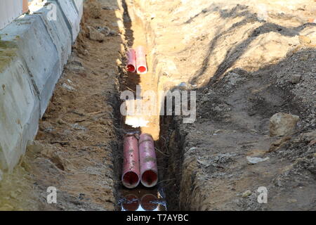 Rohre für warmes und kaltes Wasser. In den Graben sind Kunststoffrohre. Rohrleitungsbau. Es gibt keine Menschen. Stockfoto