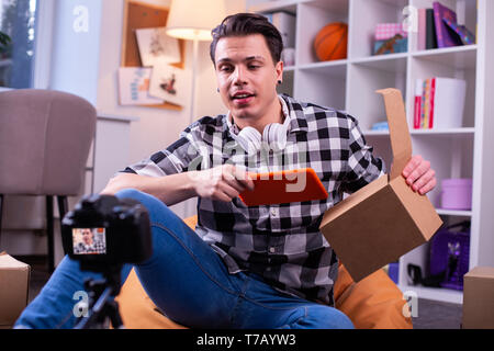 Kommunikative charismatische junge Mann in kariertem Hemd Holding neue Tablet Stockfoto