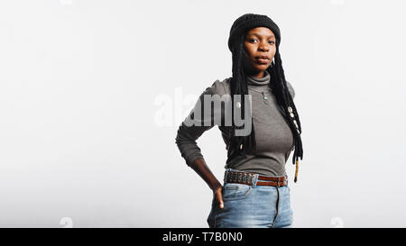 Porträt einer afrikanischen Frau in Jeans und T-Shirt mit langen dreadlocks mit Cowrie Muscheln. Afrikanische Frau mit Hand in der Tasche auf der Rückseite isoliert auf weißem Stockfoto