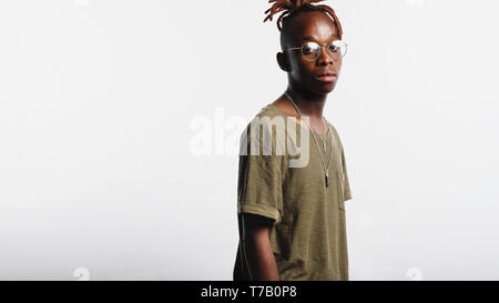 Seitenansicht eines afrikanischen Mann in Brillen gegen den weißen Hintergrund stehen. Traurig Suche afrikanischer Mann mit Dreadlocks zusammen gebunden. Stockfoto