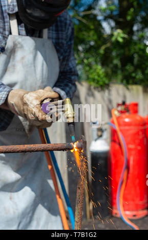 Man schneiden durch schmiedeeiserne mit einem Gasbrenner Stockfoto