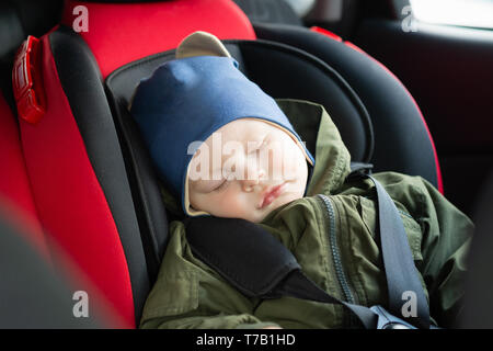 Nahaufnahme der kaukasischen Cute Baby schlafen in modernen Autositz. Kind reisen Sicherheit auf der Straße. Sicher befestigt Sicherheitsgurte im Fahrzeug zu reisen Stockfoto