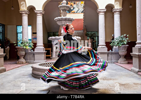 Eine mexikanische Volkstänzer im traditionellen China Poblana Kleid führt die Jarabe folkloristischen Tanz in den Arkaden im Innenhof des Rathauses in Jalostotitlan, Jalisco, Mexiko. Stockfoto