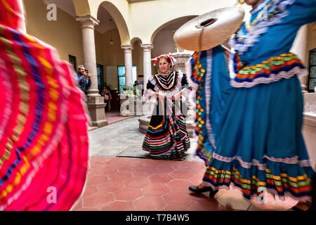 Mexikanische Volkstanzgruppe im traditionellen China Poblana Kleid führen Sie die Jarabe folkloristischen Tanz in den Arkaden im Innenhof des Rathauses in Jalostotitlan, Jalisco, Mexiko. Stockfoto