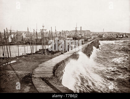 Ein Ende des 19. Jahrhunderts Blick auf stürmischer See schlagen auf die hafenmauer in Arbroath die größte Stadt in Angus, Schottland. Liegend auf der Nordsee Küste, Arbroath bekannt der schottischen Fischereiindustrie nach dem ursprünglichen Häfen, aus dem 14. und 18. Jahrhundert wurden in 1839 mit einem größeren Hafen ersetzt. Der fischwirtschaft Wuchs und auf dem Höhepunkt der Jahre zwischen 1900 und 1980, rund 40 Felchen und pelagische Schiffe arbeitete von Arbroath, mit Hunderten von Männern direkt als Fischer tätig, Hunderte mehr an Land eingesetzt, um den Fischereifahrzeugen in Service und den Fisch zu verarbeiten. Stockfoto