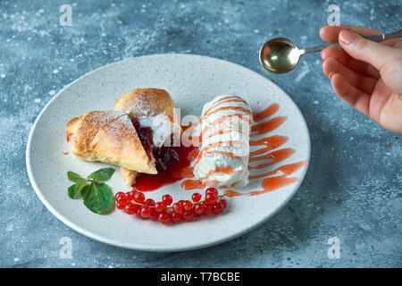 In Scheiben geschnittene Hausgemachte berry Strudel mit frischen rote Johannisbeere Beeren und Puderzucker auf einem alten Hintergrund auf einer Platte mit Eis pic serviert. Stockfoto
