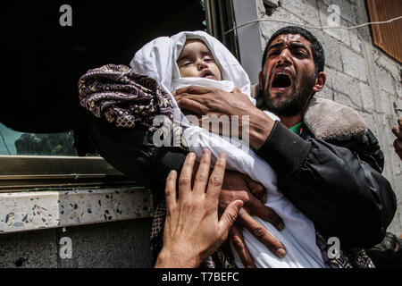 Mai 5, 2019 - Gaza, Gazastreifen - Verwandten vorbereiten für das Begräbnis des 14 Monate alten Saba Mahmoud Abu Arar, die ihr Leben in einem israelischen Luftangriff, die ihr Haus in den al-Zaytoun Nachbarschaft am Samstag hit verloren. Seba der schwangeren Mutter wurde schwer verwundet und später am Abend enthalten. Der Luftangriff erfolgte in Israel war die Durchführung einer intensiven aerial Offensive im Gazastreifen nach der Einleitung einer Reihe von Raketen aus dem Gazastreifen in Israel (Bild: © Ahmad Hasaballah/IMAGESLIVE über ZUMA Draht) Stockfoto