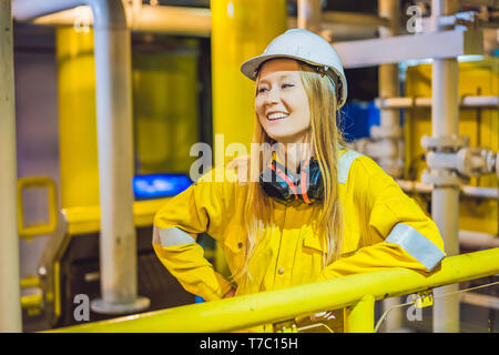 Junge Frau in einem gelben Arbeiten einheitliche, Brille und Helm in industrieller Umgebung, Ölplattform oder verflüssigte Gas-Anlage Stockfoto