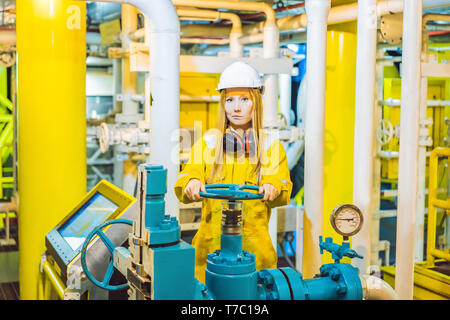 Junge Frau in einem gelben Arbeiten einheitliche, Brille und Helm in industrieller Umgebung, Ölplattform oder verflüssigte Gas-Anlage Stockfoto