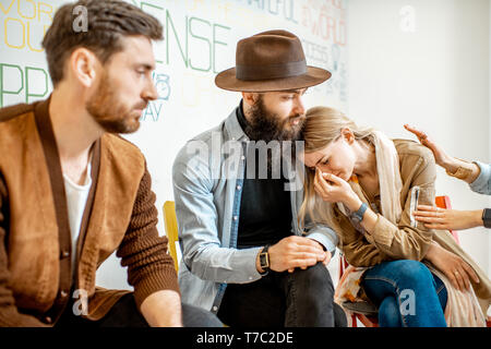 Junge Frau weinen während der psychologischen Therapie mit Gruppe von Menschen ihre Unterstützung im Büro Stockfoto