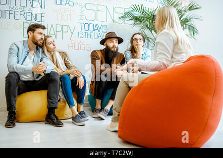 Zwei junge Paare während der psychologischen Therapie mit Psychologen sitzen, lösen einige mentale Probleme im modernen Büro Stockfoto