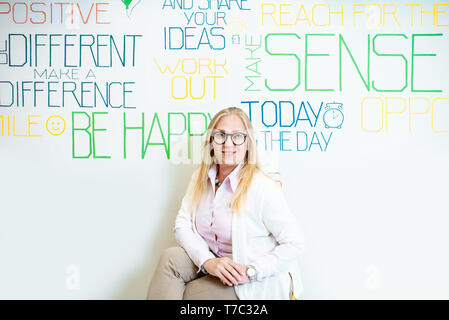 Porträt einer älteren Frau als Mental Coach an der Wand Hintergrund mit verschiedenen Inschriften auf das Thema der psychischen Gesundheit im Innenbereich Stockfoto