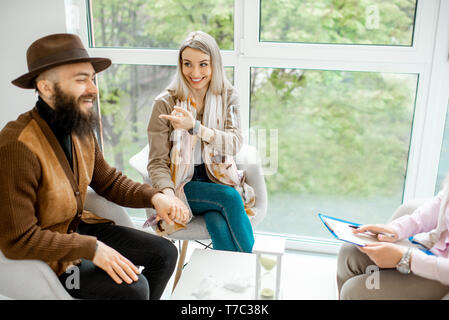 Junge glückliches Paar Sitzen mit dem Psychologen während der psychologischen Beratung im Büro Stockfoto