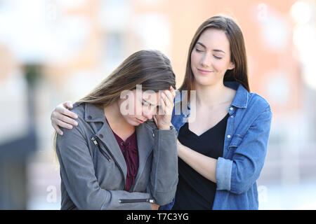 Heuchler schlecht Frau trösten Sie traurig Freund, der in der Straße beschwert, Stockfoto