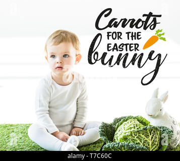 Cute Baby in der Nähe von Wirsing und dekorative Kaninchen sitzend mit Karotten für den Osterhasen Abbildung auf weißem Hintergrund Stockfoto