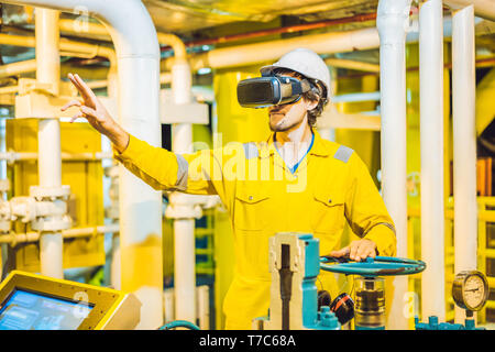 Junge Frau in einem gelben Arbeiten einheitliche, Brille und Helm mit Virtual reality Brillen in industrieller Umgebung, Ölplattform oder verflüssigte Gas-Anlage Stockfoto