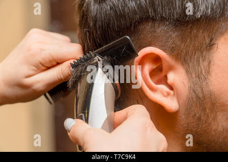 Frau Friseur schneidet die Haare des Mannes mit elektrischer Haarschneider Trimmer Stockfoto