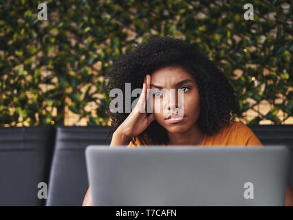 Betrachtet junge Frau im Cafe mit Laptop Stockfoto