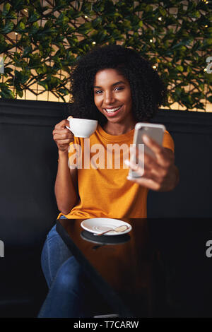 Eine attraktive Lächelnden jungen Frau unter selfie auf Handy im Cafe Stockfoto
