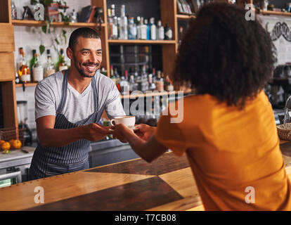 Männliche Barista serviert Kaffee Tasse für weibliche Kunden im Cafe Stockfoto