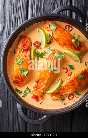 Thai würziger Kokosnuss curry mit Lachs close-up in einer Pfanne auf dem Tisch. Vertikal oben Ansicht von oben Stockfoto