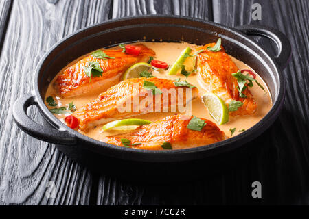 Asiatische Küche. Lachs mit Kokosnuss Sauce, Kalk und Kräuter close-up in einer Pfanne auf dem Tisch. Horizontale Stockfoto