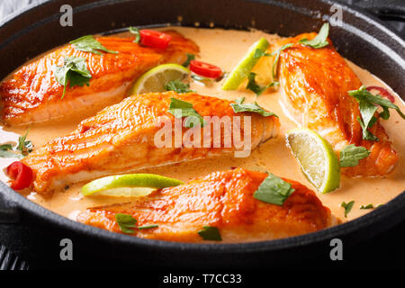 Gekochter Lachs in einer würzigen coconut Sauce mit Kalk und Kräuter close-up in einer Pfanne auf dem Tisch. Horizontale Stockfoto