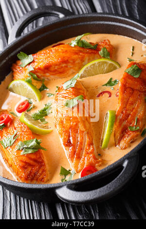 Thai würziger Kokosnuss curry mit Lachs close-up in einer Pfanne auf dem Tisch. Vertikale Stockfoto