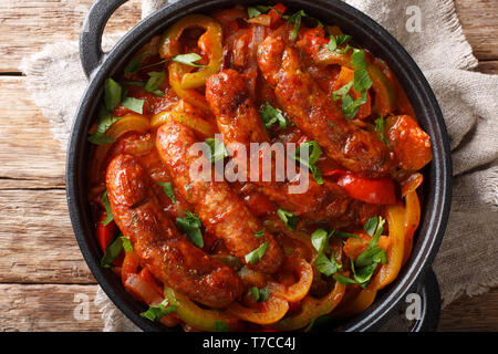 Traditionelle gegrillte Würstchen mit buntem Paprika, Zwiebeln und Tomaten close-up in einer Pfanne auf dem Tisch. horizontal oben Ansicht von oben Stockfoto