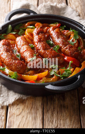 Köstliche italienische Wurst vom Grill mit Paprika, Zwiebeln und Tomaten close-up in einer Pfanne auf dem Tisch. Vertikale Stockfoto