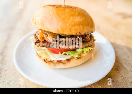 Hausgemachte Hamburger mit frischem Gemüse, frische leckere Burger mit, Essiggurken, Tomaten, karamellisierten Zwiebeln und Salat Stockfoto