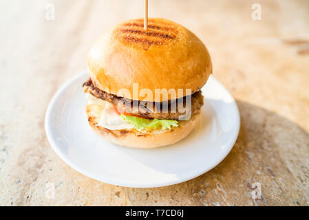 Hausgemachte Hamburger mit frischem Gemüse, frische leckere Burger mit, Essiggurken, Tomaten, karamellisierten Zwiebeln und Salat Stockfoto