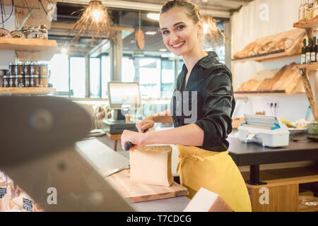 Shop clerk in deli Schneiden von Käse Stockfoto