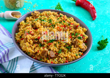 Bulgur mit Huhn und Gemüse. Leckeren, gesunden warmen Salat auf einem hellen Hintergrund. Bulgur pilaw. Nahaufnahme Stockfoto