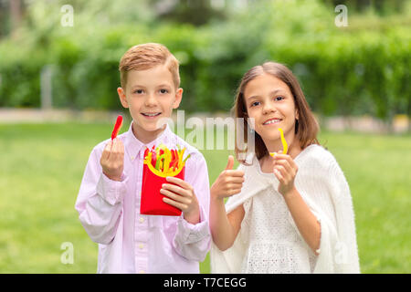 Lächelnde Kinder das Essen von frischem Gemüse in Form von Pommes Frites geschnitten Stockfoto