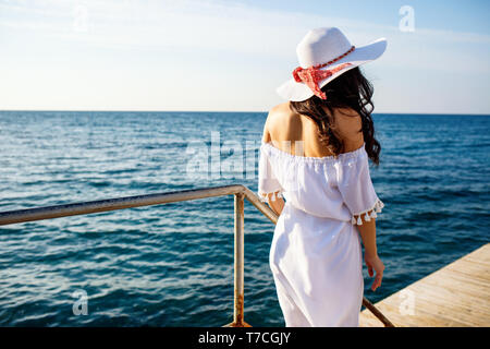 Zurück auf Frau in Weiß Sommer Kleid zu Fuß auf hölzernen Pier sehen. Stockfoto