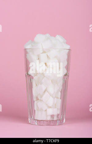 Trinken Glas von Pauschalbeträgen Würfelzucker auf Rosa pastell Hintergrund. Unhealthly Ernährung mit süßen zuckerhaltigen Softdrinks Konzept. Stockfoto