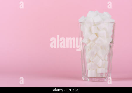 Trinken Glas von Pauschalbeträgen Würfelzucker auf Rosa pastell Hintergrund. Unhealthly Ernährung mit süßen zuckerhaltigen Softdrinks Konzept. Stockfoto