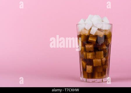 Trinken Glas von Klumpen Zucker Würfel und weich Cola trinken auf Rosa pastell Hintergrund. Unhealthly Ernährung mit süßen zuckerhaltigen Softdrinks Konzept. Stockfoto