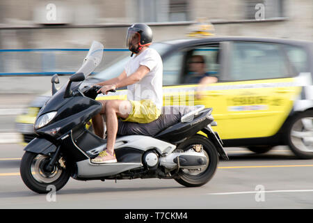 Belgrad, Serbien - April 26, 2019: Ein Mann reiten Roller in Stadt Straße Verkehr und blurry Taxi Auto hinter Stockfoto