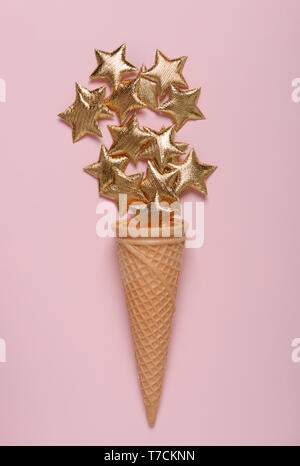 Eis mit glänzenden goldenen Sternen auf Rosa pastell Hintergrund flatlay Stockfoto