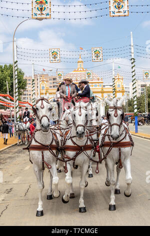 Sevilla, Spanien - 5. Mai 2019: Menschen, die auf die Kutsche zu der Messe mit dem Haupteingang der Messe von Sevilla am Mai 5, 2019 in Sevilla Stockfoto